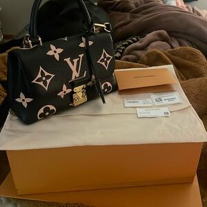 Black Louis Vuitton hand bag, with gold detailing, red lining, and monogram.